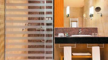 A modern bathroom with a glass shower enclosure, a black countertop sink, and two wall-mounted mirrors.