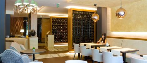 Un'area lounge moderna con posti a sedere, una cantinetta e una donna seduta a un tavolo.
