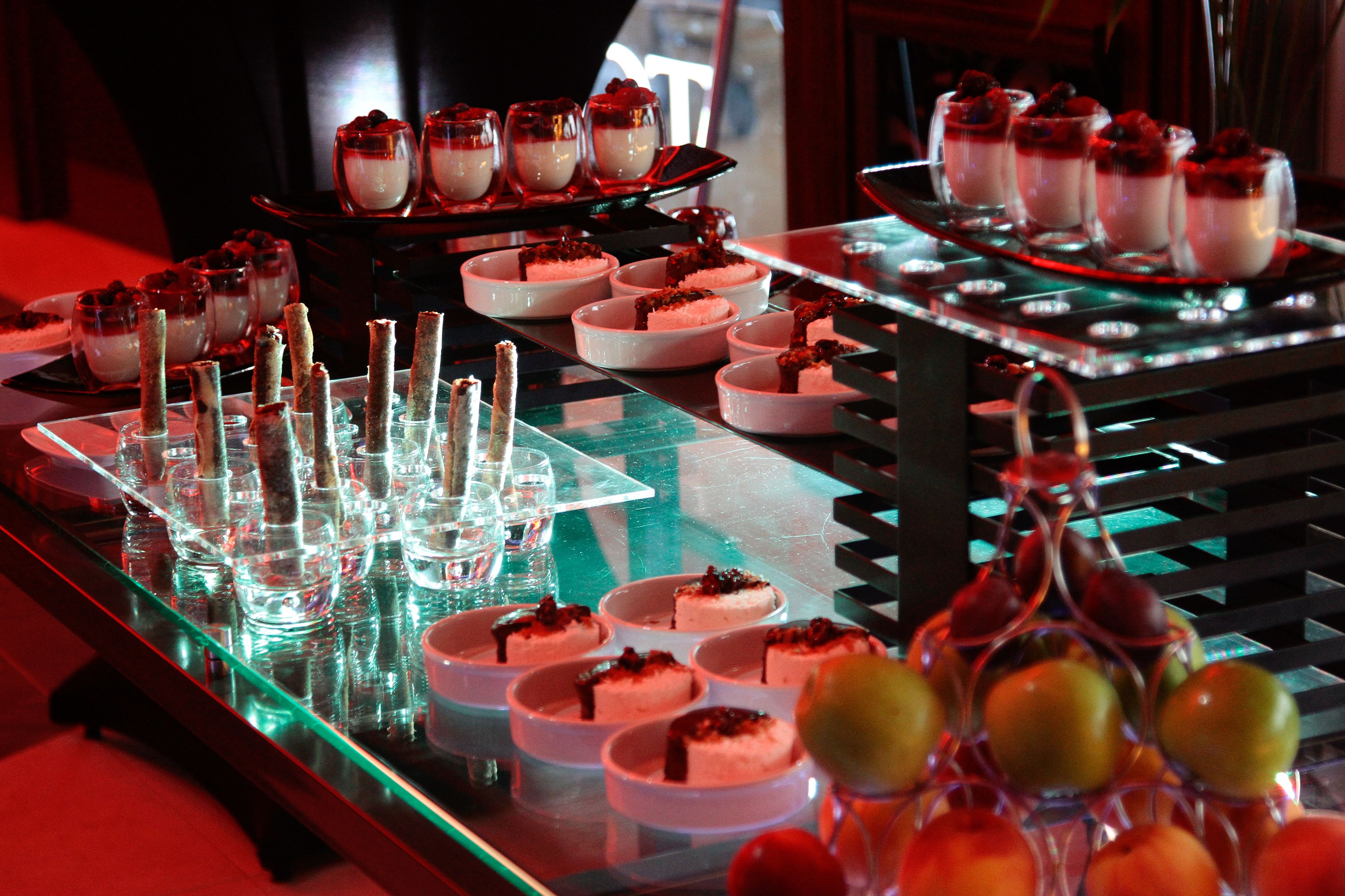 Un bufé de postres con diversos platos pequeños y vasos.