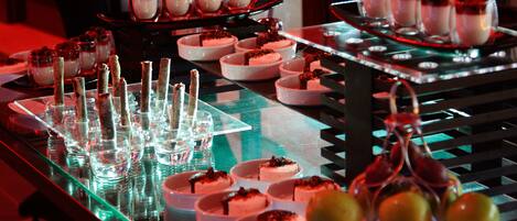 Un bufé de postres con diversos platos pequeños y vasos.