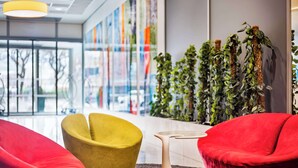 Un interior moderno con sillas rojas y amarillas, una mesa original e instalaciones verticales de plantas.