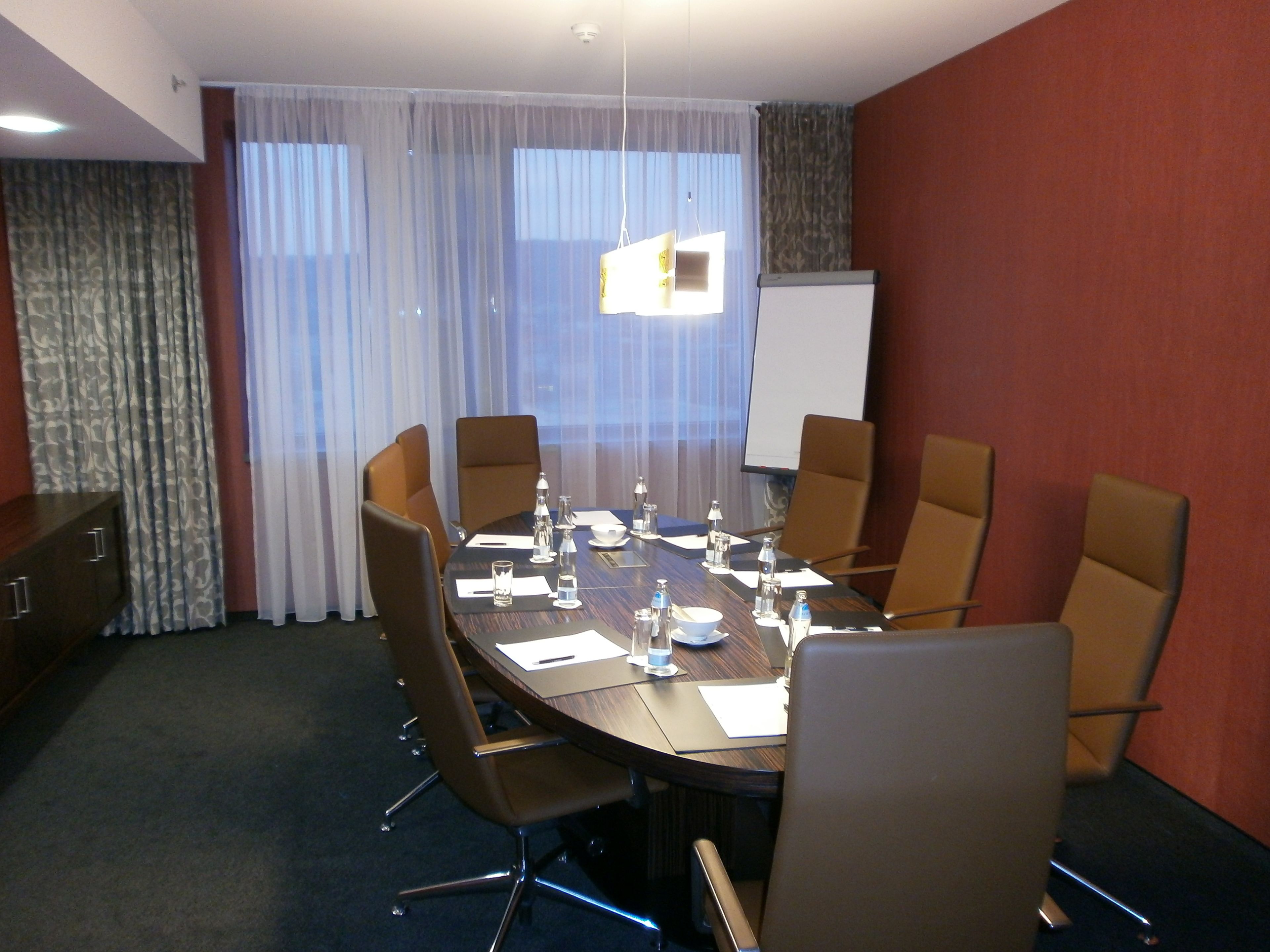A conference room with a large table, chairs, a whiteboard, and a projector screen.