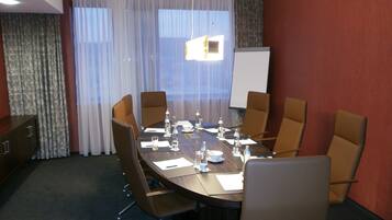 A conference room with a large table, chairs, a whiteboard, and a projector screen.