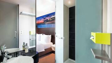 A modern hotel bathroom with a large sink, a mirror, and a shower area.