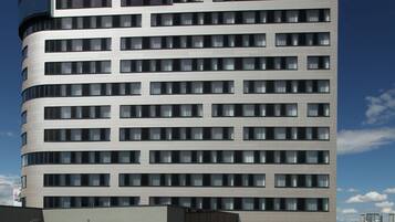 A modern hotel building with a curved facade, multiple floors, and a prominent sign at the top.