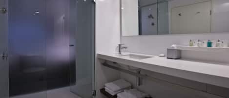 A modern bathroom with a glass-enclosed shower, a white sink, and a large mirror.