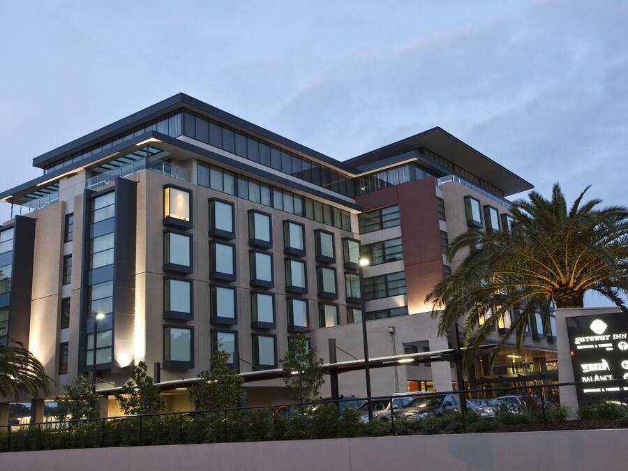 Een modern hotel met meerdere verdiepingen, grote ramen en een bord waarop staat Gateway Inn.