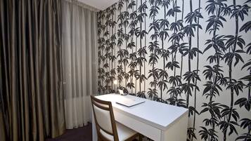 A room with a white desk, a wooden chair, and a wall with a bamboo pattern.