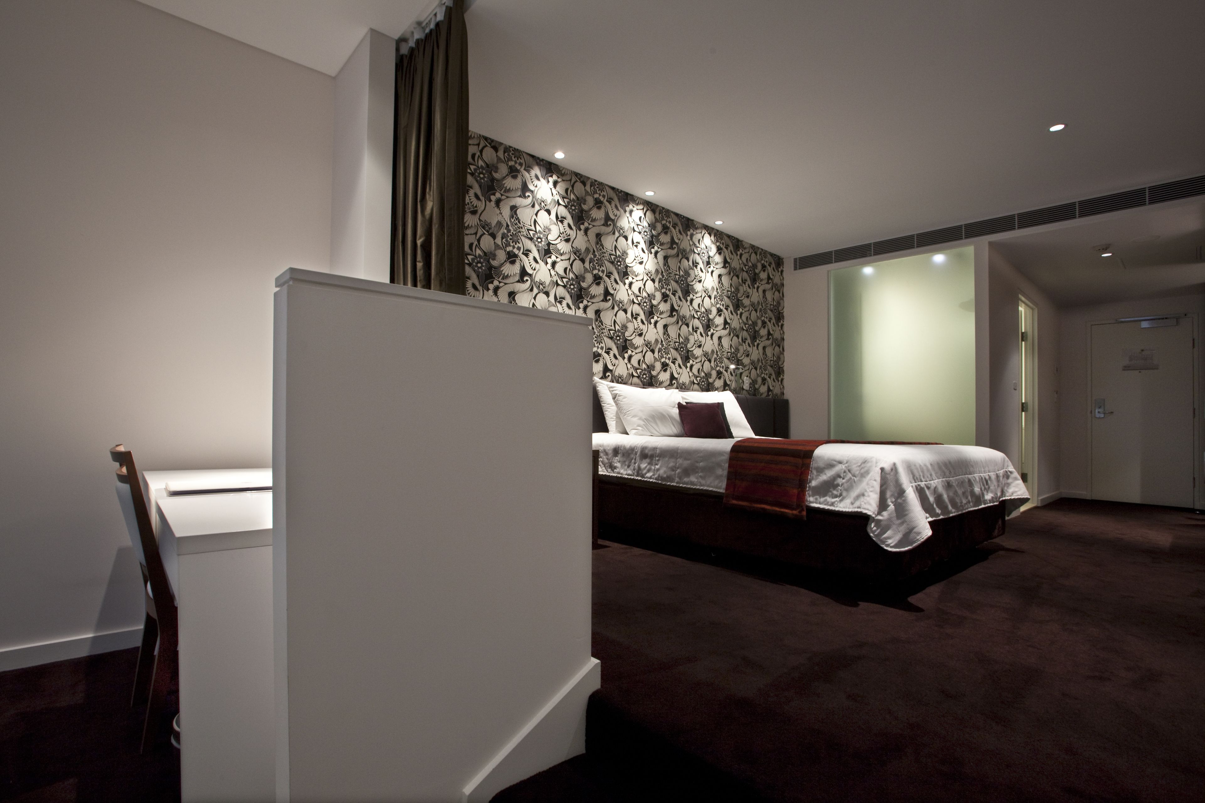 Ein modernes Hotelzimmer mit einem Bett, einem Schreibtisch und einer Wand mit Muster.