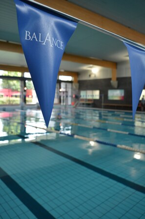 A swimming pool with blue lane dividers and a banner reading "BALANCE".