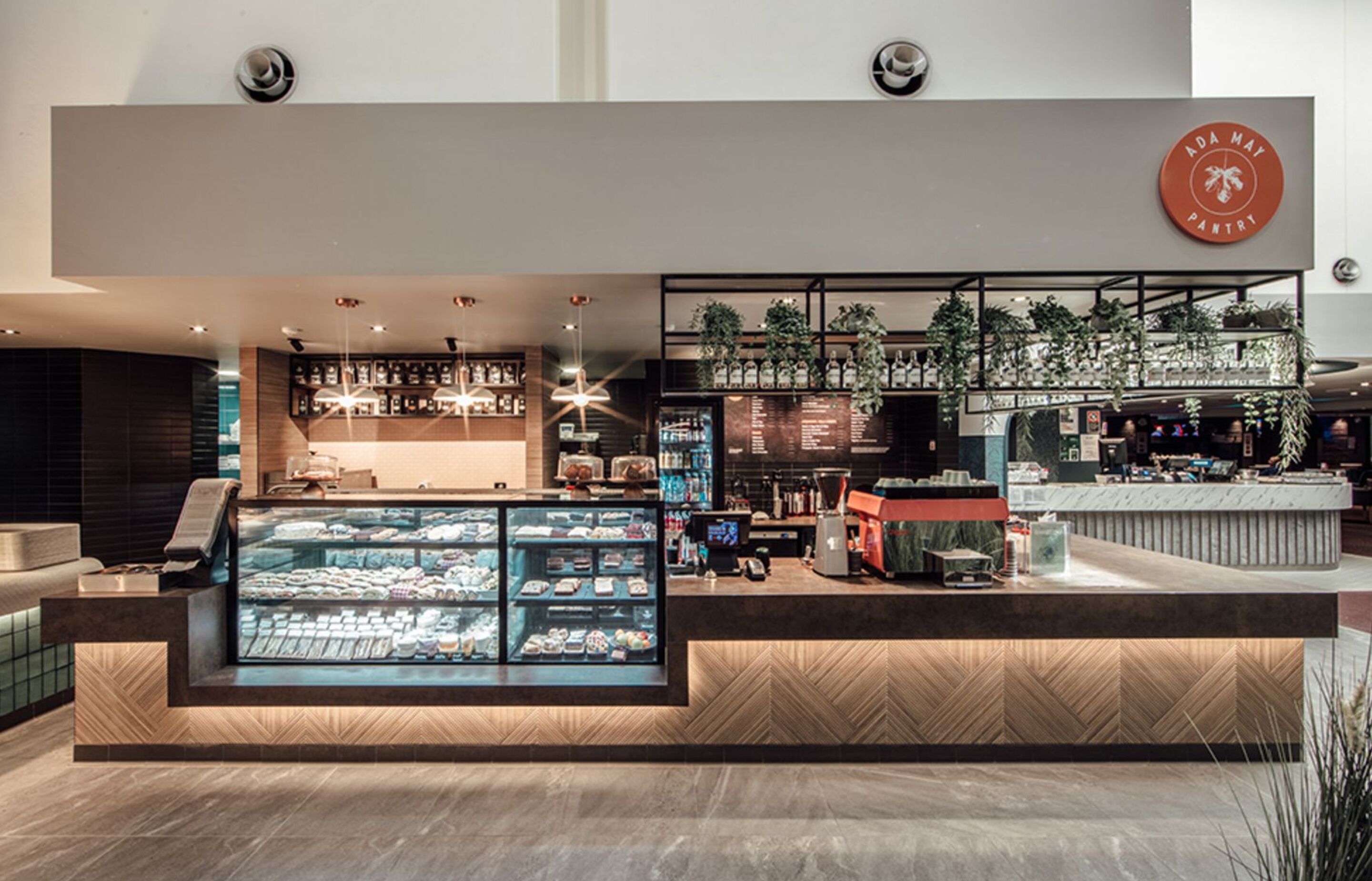 A modern interior with a bakery counter, display cases, and a coffee bar.