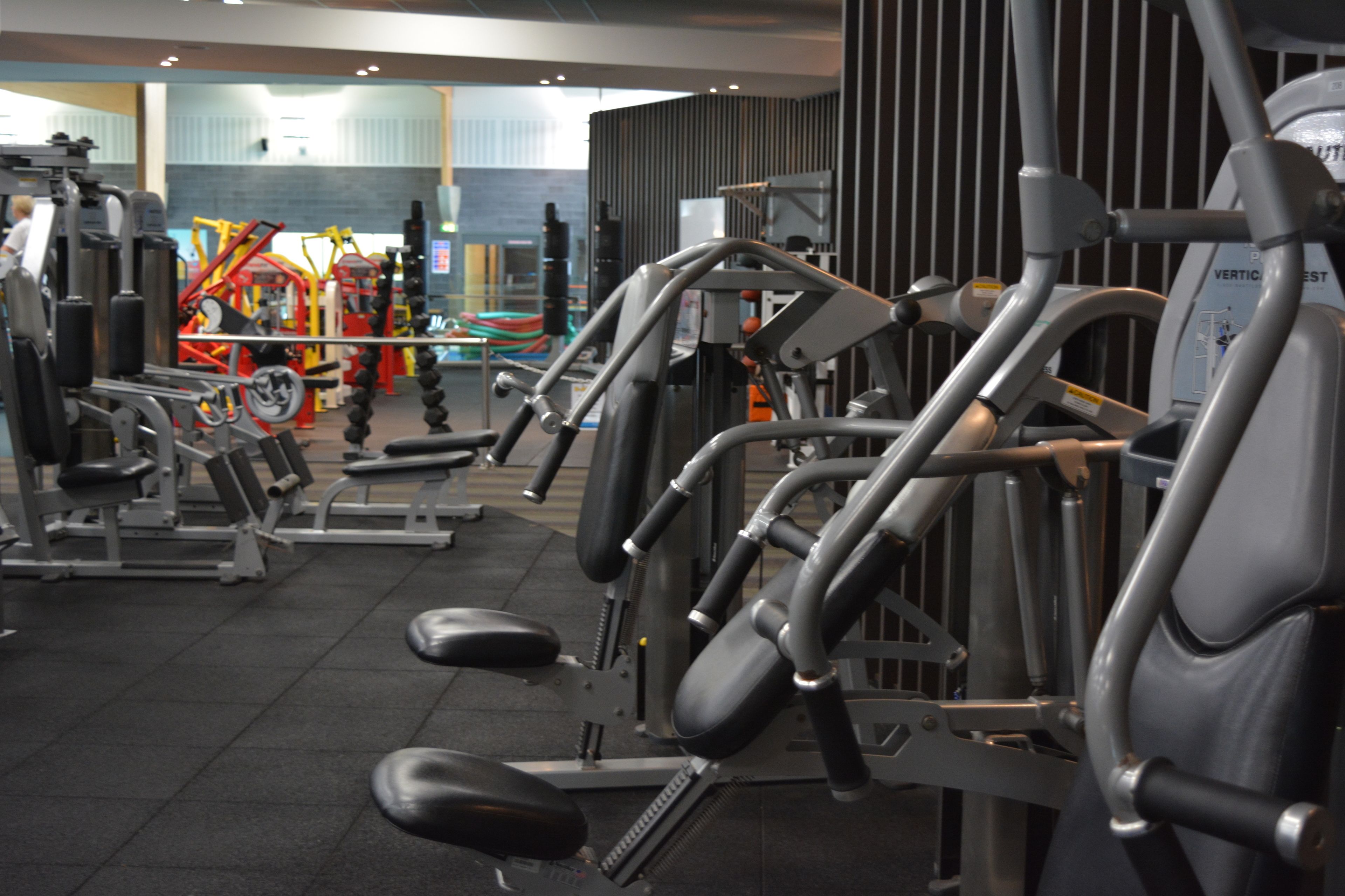 Un gimnàs amb diverses màquines d'exercici, incloent piles de peses i equipament cardiovascular.