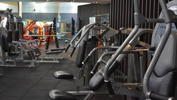 Un gimnàs amb diverses màquines d'exercici, incloent piles de peses i equipament cardiovascular.