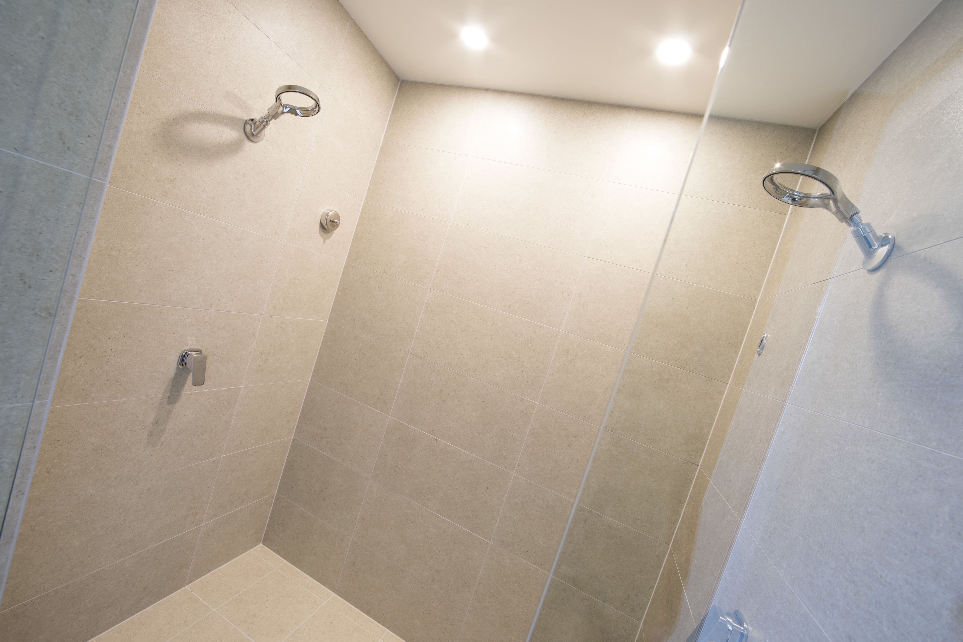 Un área de ducha pequeña y cerrada con puerta de vidrio y ducha en la pared.