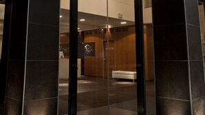 A modern interior with a glass elevator, dark walls, and recessed lighting.