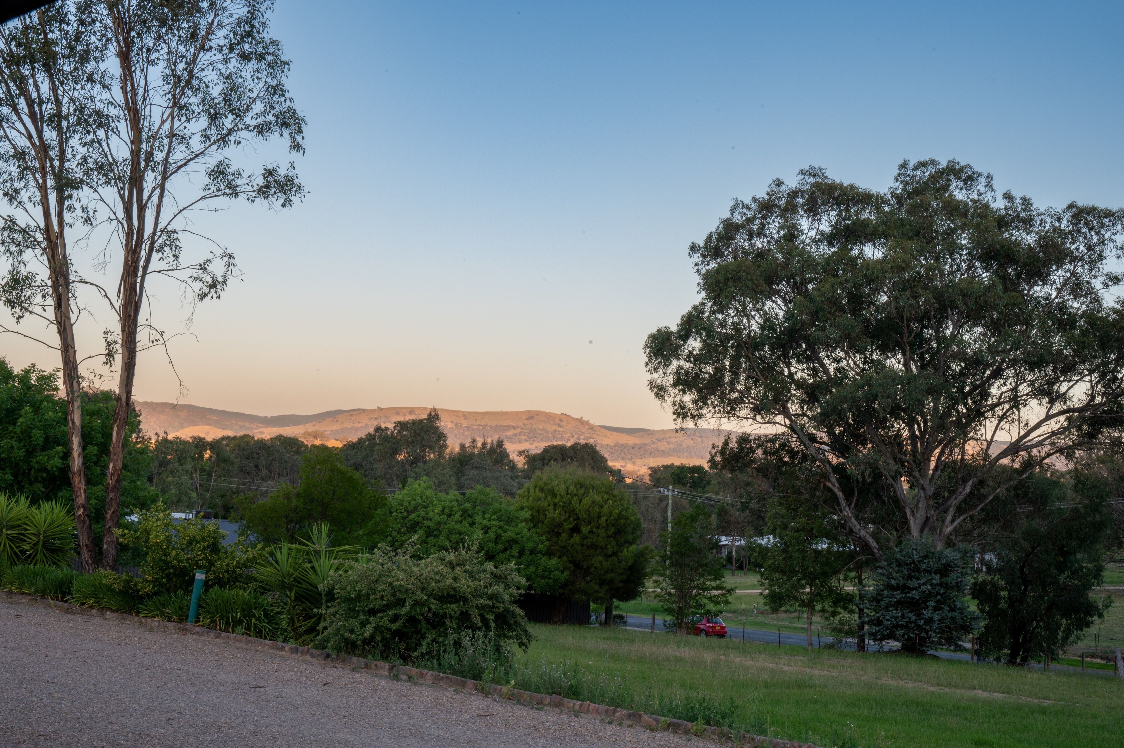 Ländliche Landschaft mit einer Straße, Bäumen und einem fernen Gebirge.