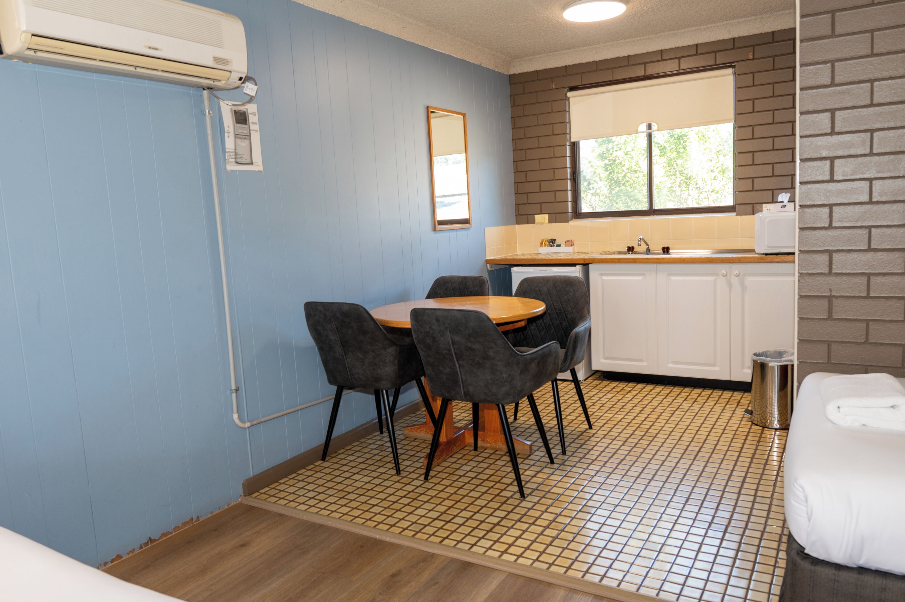 Una habitación compacta con una mesa y sillas, una kitchenette pequeña y un ventanal con vistas.
