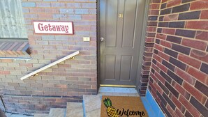 A brick building with a 'Getaway' sign and a 'Welcome' mat at the entrance.