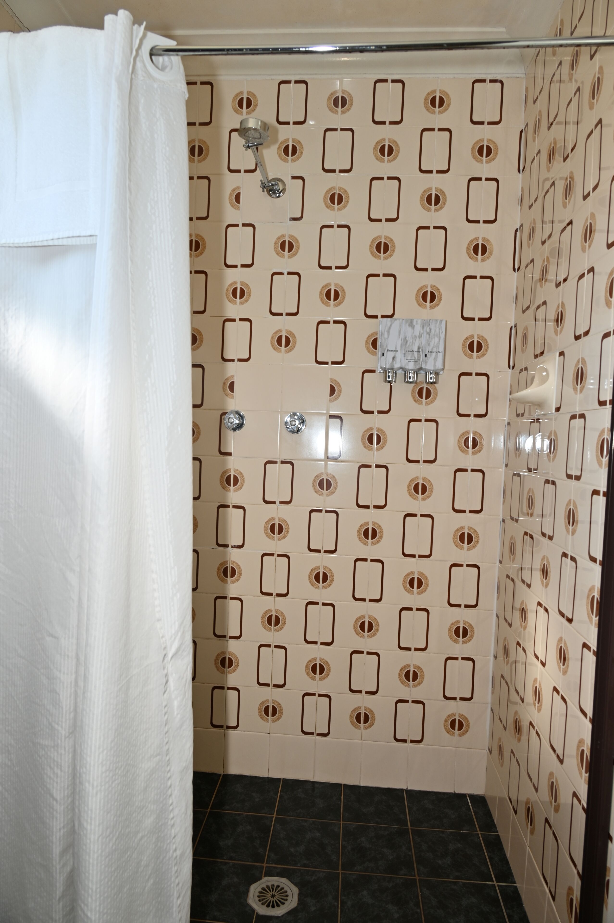 A shower area with a patterned tile wall, a showerhead, and a drain.
