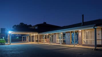 A hotel with a covered outdoor area, multiple rooms with large windows, and a sign indicating amenities like a pool and internet.