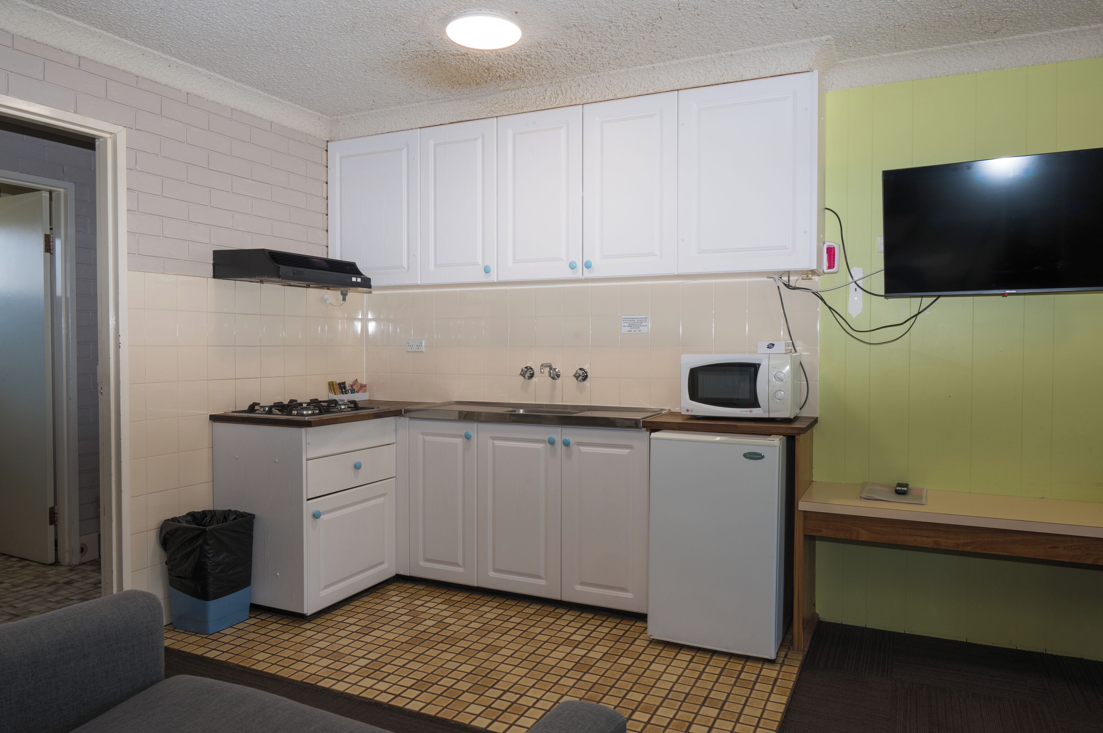 A compact kitchen with white cabinets, a microwave, and a small refrigerator.