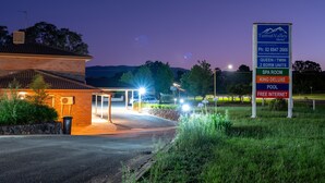 A motel with a sign listing amenities including a spa room, King Deluxe pool, and free internet.
