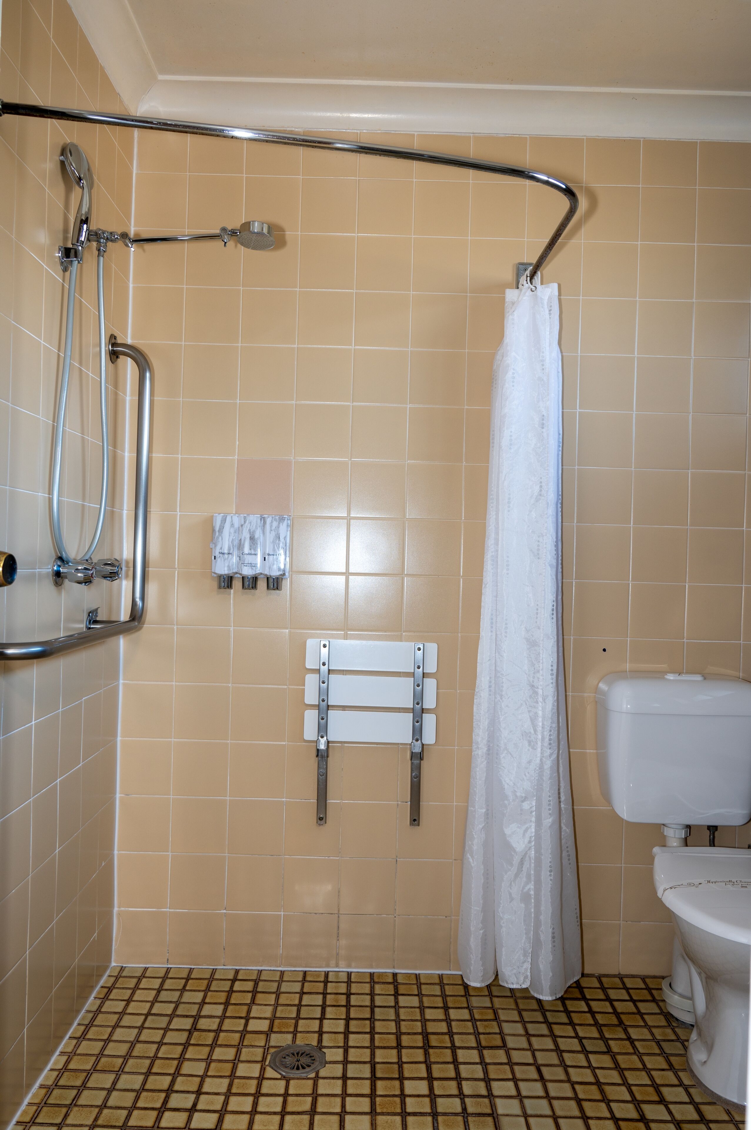 Ein Badezimmer mit Dusche, Toilette und Fliesenboden.