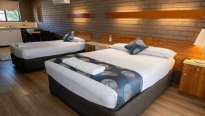 A hotel room with two beds, a small desk, and a bathroom.