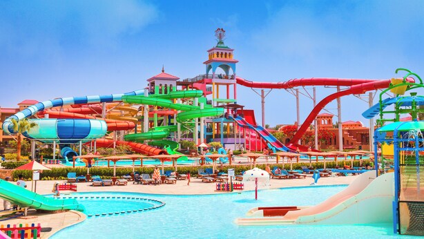 A water park with multiple slides and pools, a tower, and lounge areas.