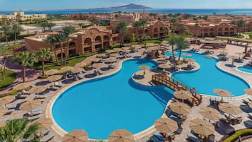 Een buitenzwembad, parasols bij het zwembad en ligstoelen