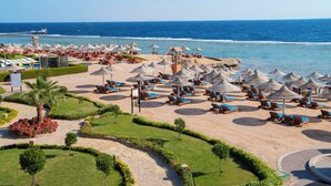 A beach resort with sun loungers, umbrellas, and a view of the ocean.