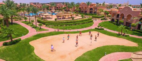 Un resort con una arena central, palmeras y una zona de piscina.