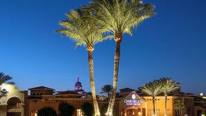 A hotel with a prominent sign, palm trees, and a clear sky.