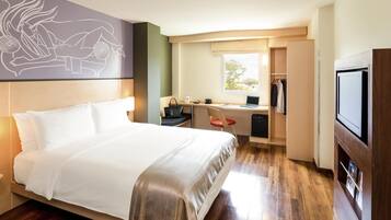 A hotel room with a bed, desk, chair, and TV.