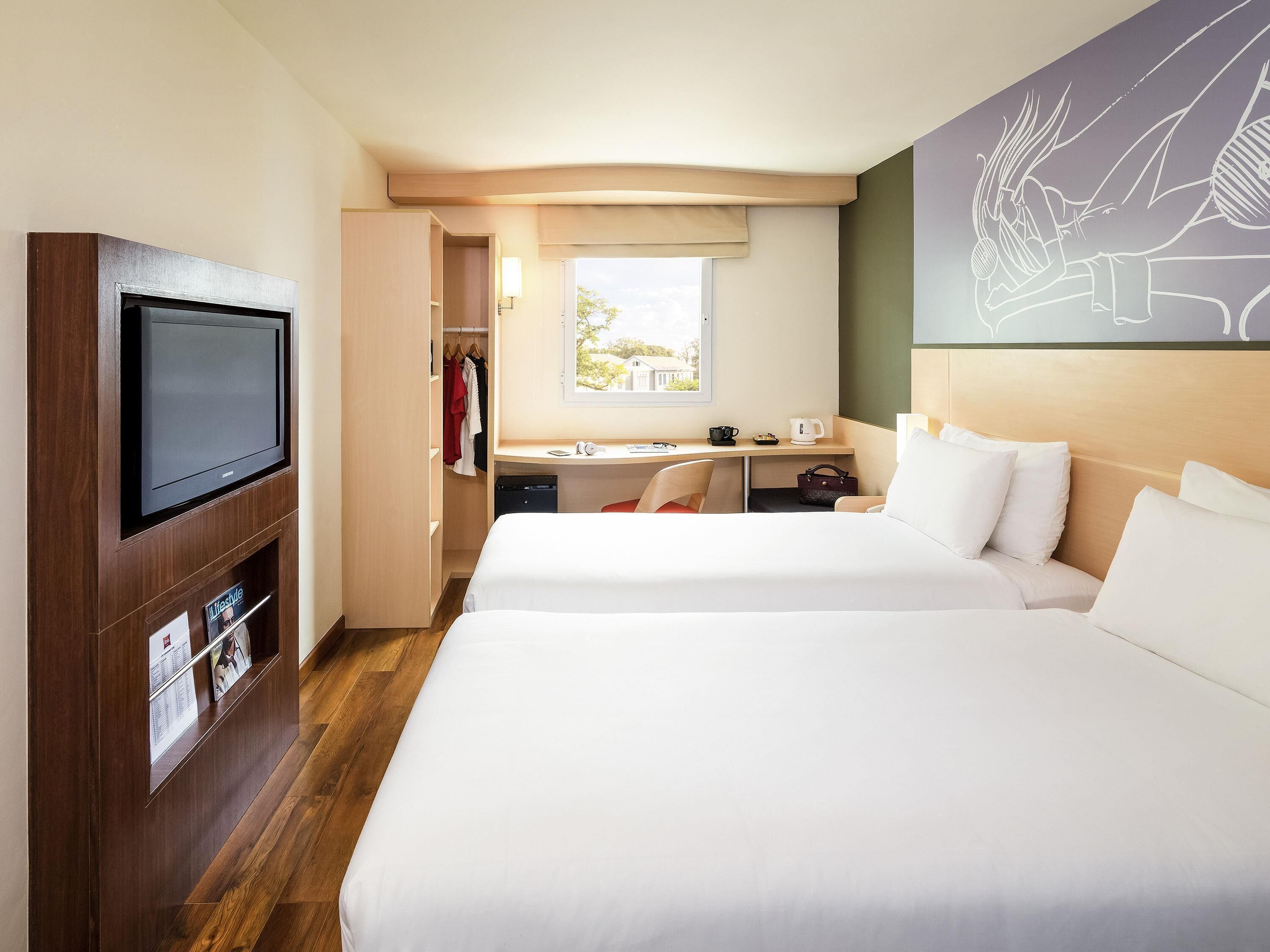 Une chambre d’hôtel avec deux lits, un bureau, une télévision et un placard.