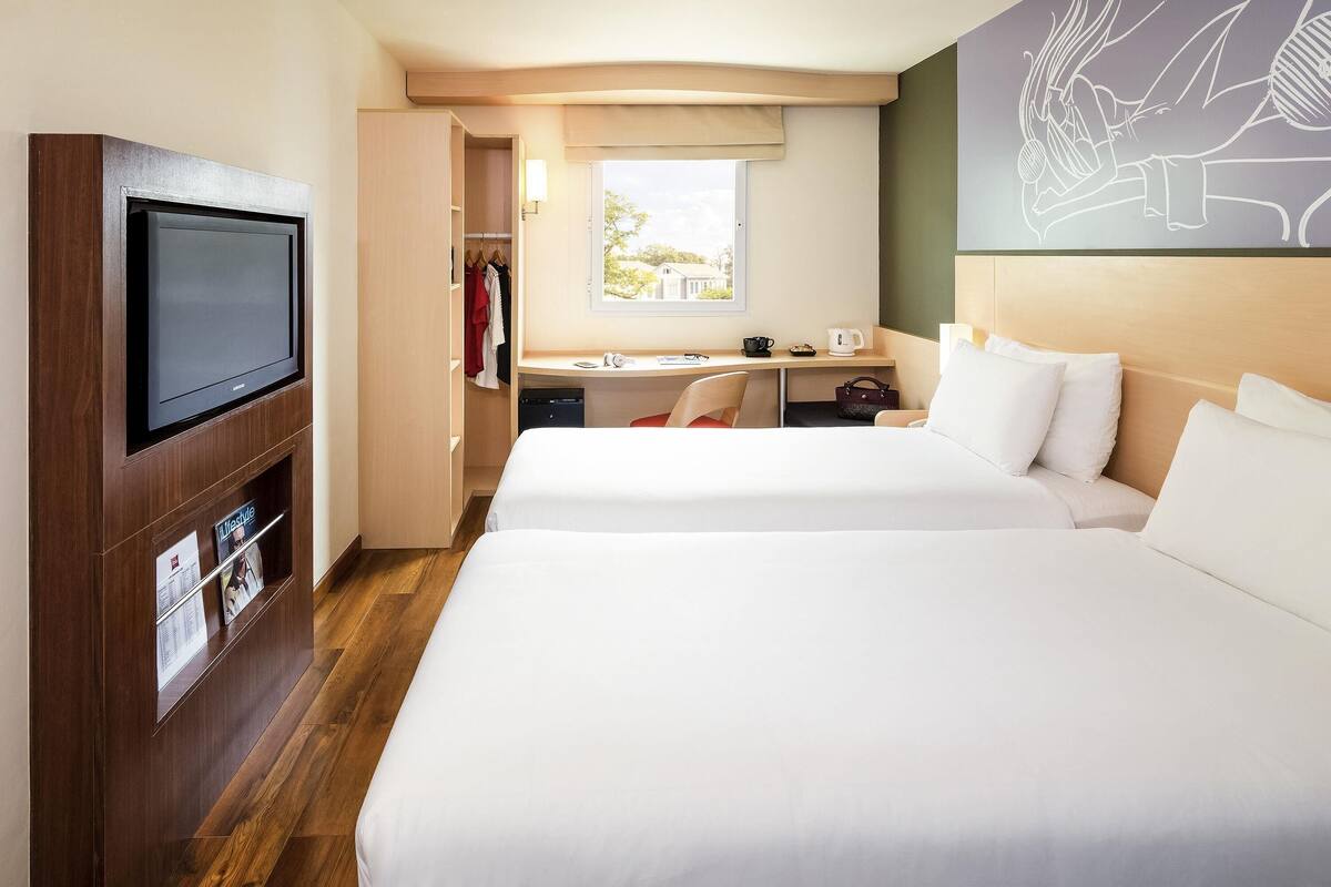 Ett hotellrum med två sängar, ett skrivbord, en tv och en garderob.
