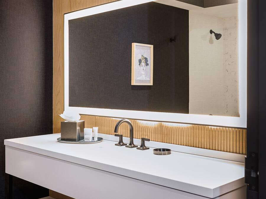A modern bathroom with a large mirror, white vanity, and wooden paneling.
