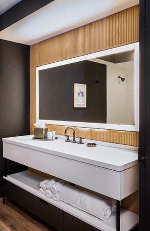 A modern bathroom with a large mirror, white vanity, and wooden paneling. - The Watershed (Norwalk)
