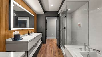 Een moderne badkamer met een houten wastafelmeubel, een grote spiegel, een douchecabine van glas en een bad.