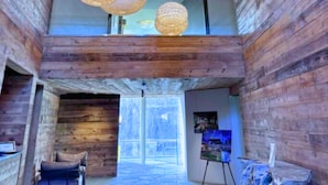 A wooden interior with hanging woven light fixtures, a seating area, and a view of the outdoors. - The Watershed (Norwalk)