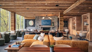 A modern living room with a stone fireplace, large windows, and a cozy seating area. - The Watershed (Norwalk)
