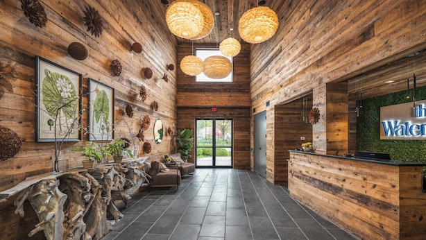 A wooden interior with a reception desk, framed botanical prints, and a sign reading "The Water." - The Watershed (Norwalk)