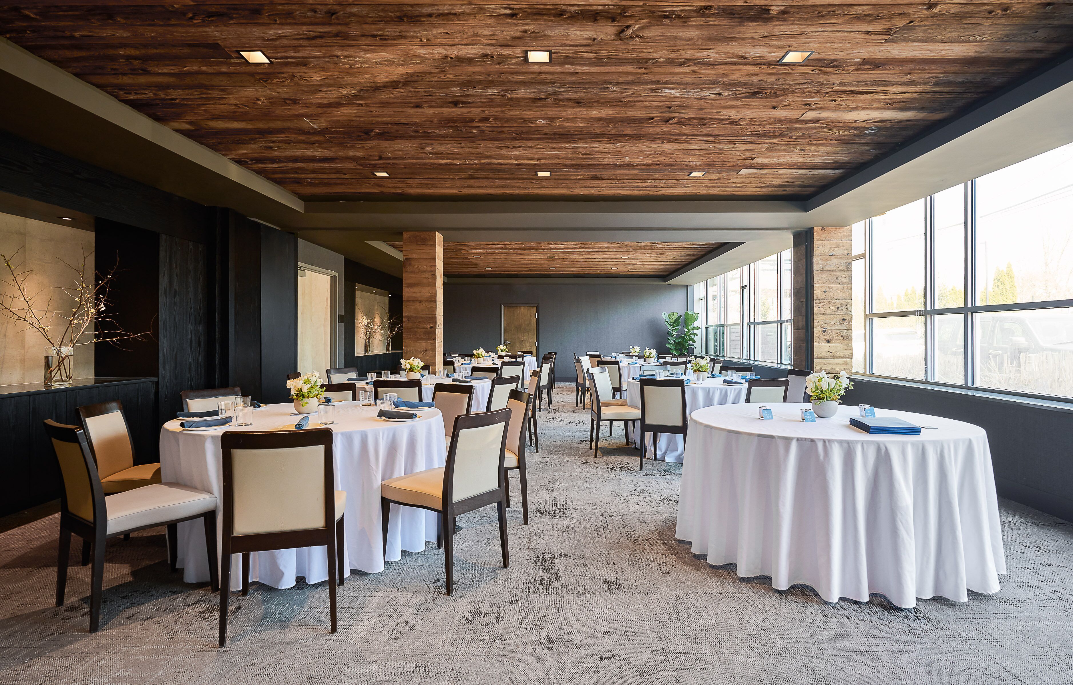 A conference room with round tables, chairs, and a carpeted floor.