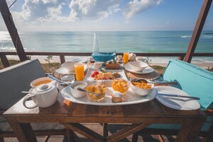 A breakfast table with various dishes and a view of the ocean.