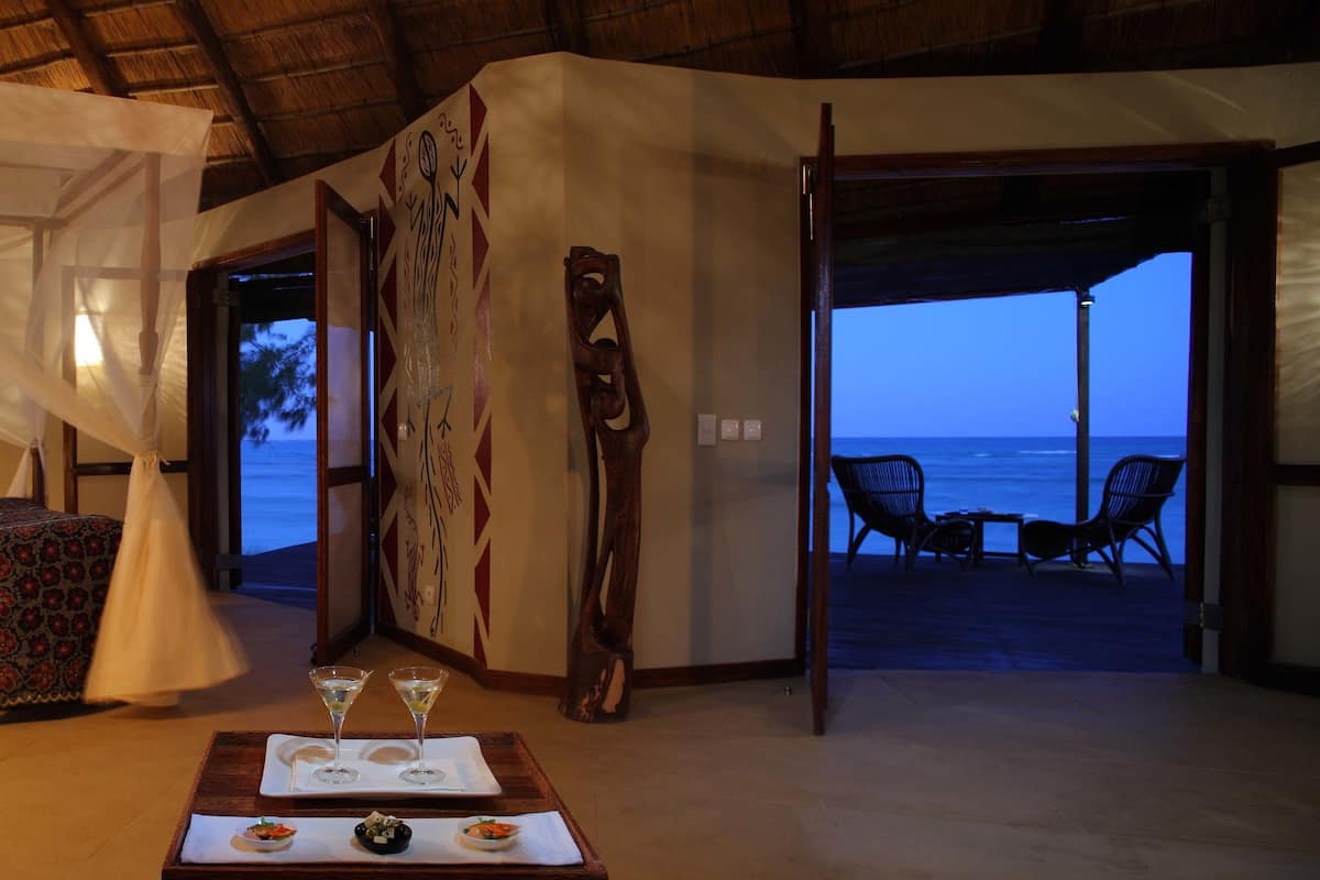 Una habitación con cama, una mesa con bebidas y vista al océano.