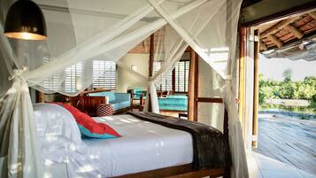 A spacious bedroom with a large bed, a canopy, and a view of the outdoors.