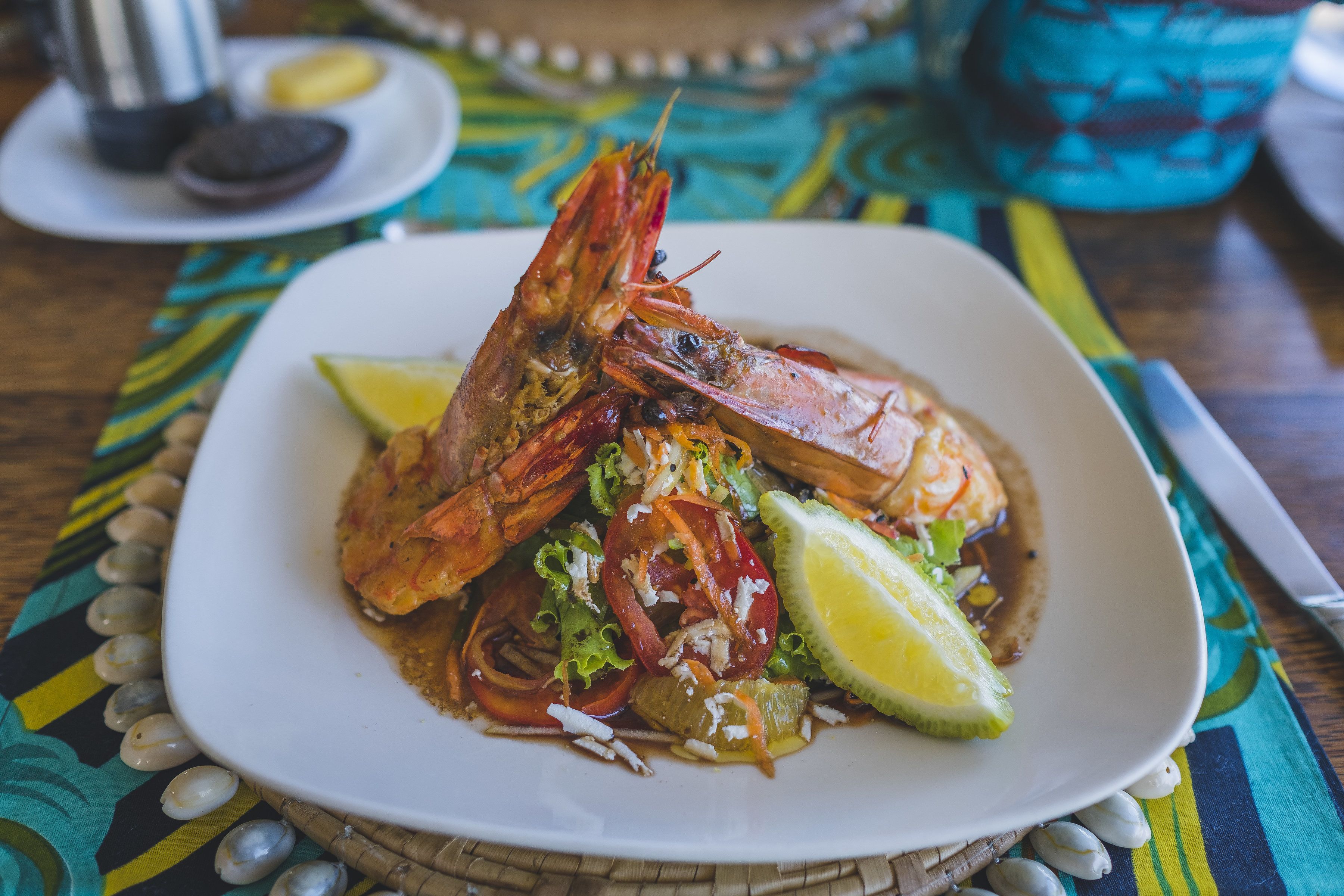 Un plato de comida con camarones y vegetales sobre un mantel colorido.