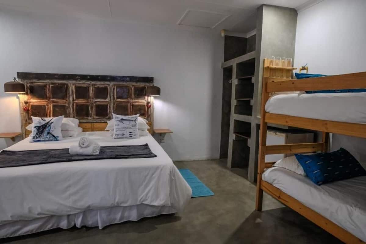 Quarto com beliche, escrivaninha e prateleira na parede com copos.