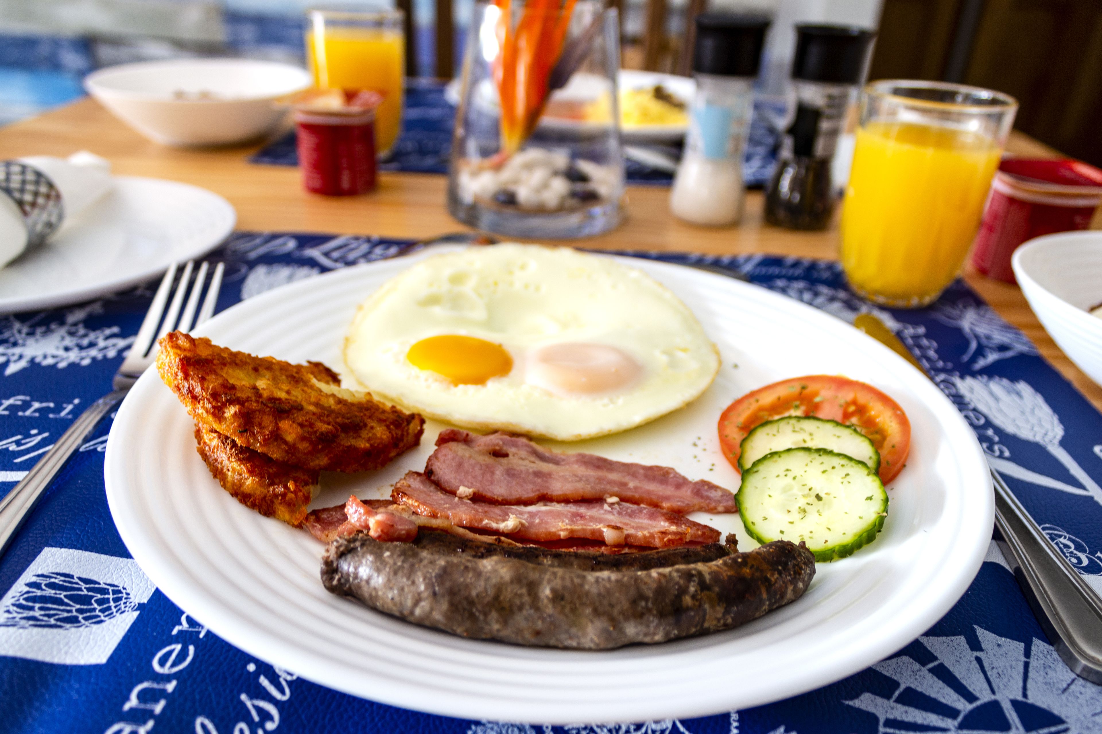 Ein Frühstücksteller mit Eiern, Speck, Wurst und Gemüse.