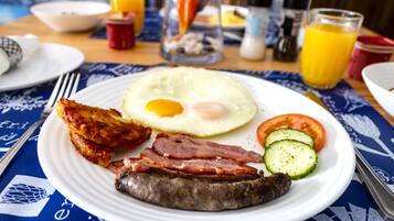 Ein Frühstücksteller mit Eiern, Speck, Wurst und Gemüse.